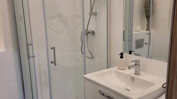 A modern bathroom with a glass-enclosed shower, a white sink, and a mirror.