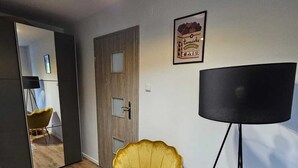 Una sala de estar moderna con un sillón amarillo, un espejo grande, una lámpara de pie negra y una alfombra.