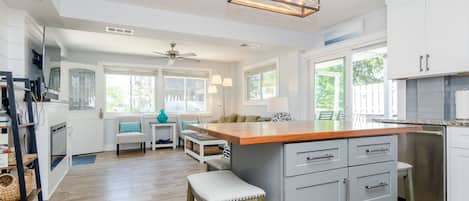 A spacious kitchen with a central island, white cabinetry, and a ceiling fan.