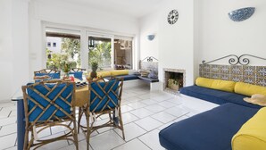 Ein heller Raum mit Esstisch, Stühlen, einer Couch und einem Kamin.