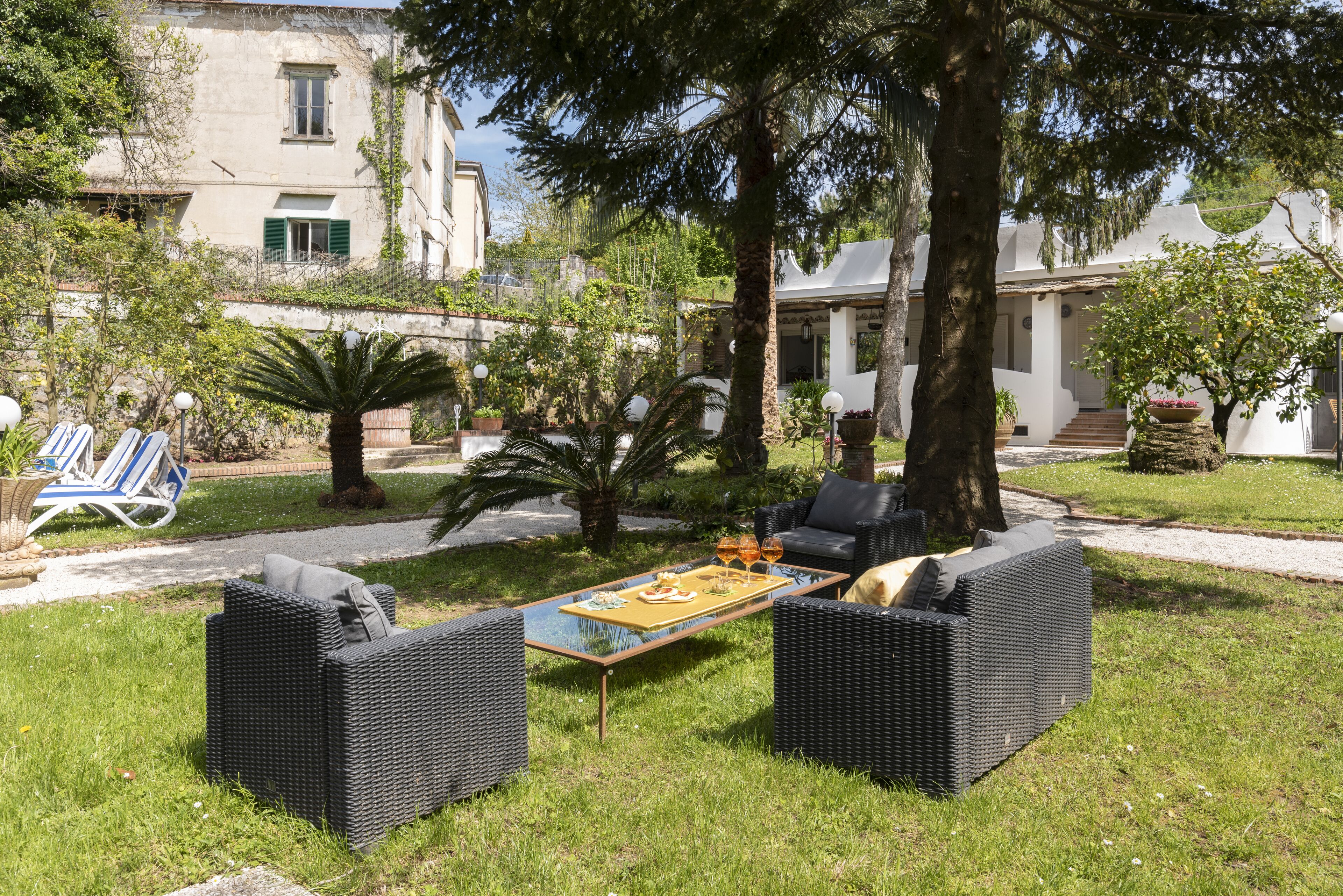 A garden area with outdoor furniture, a dining table, and a pathway leading to a building.