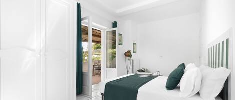 A bedroom with a bed, a nightstand, a chair, and a view of an outdoor patio.