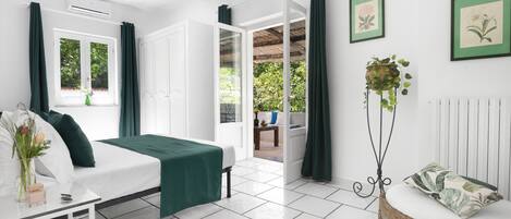 A modern bedroom with a bed, bedside table, and a view of the garden.