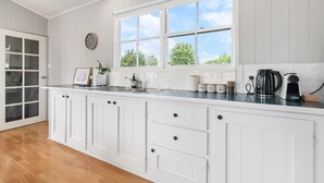 A kitchen with white cabinetry, a large window, and a clock on the wall. - Loft Ninety Three | Stylish & Central (Orange)
