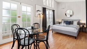 A room with a bed, a round mirror, a dining table with chairs, and a large window with frosted glass panels. - Loft Ninety Three | Stylish & Central (Orange)