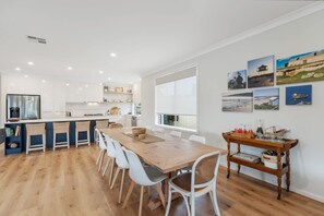 Une cuisine moderne avec des meubles blancs, une table à manger en bois et une grande fenêtre.
