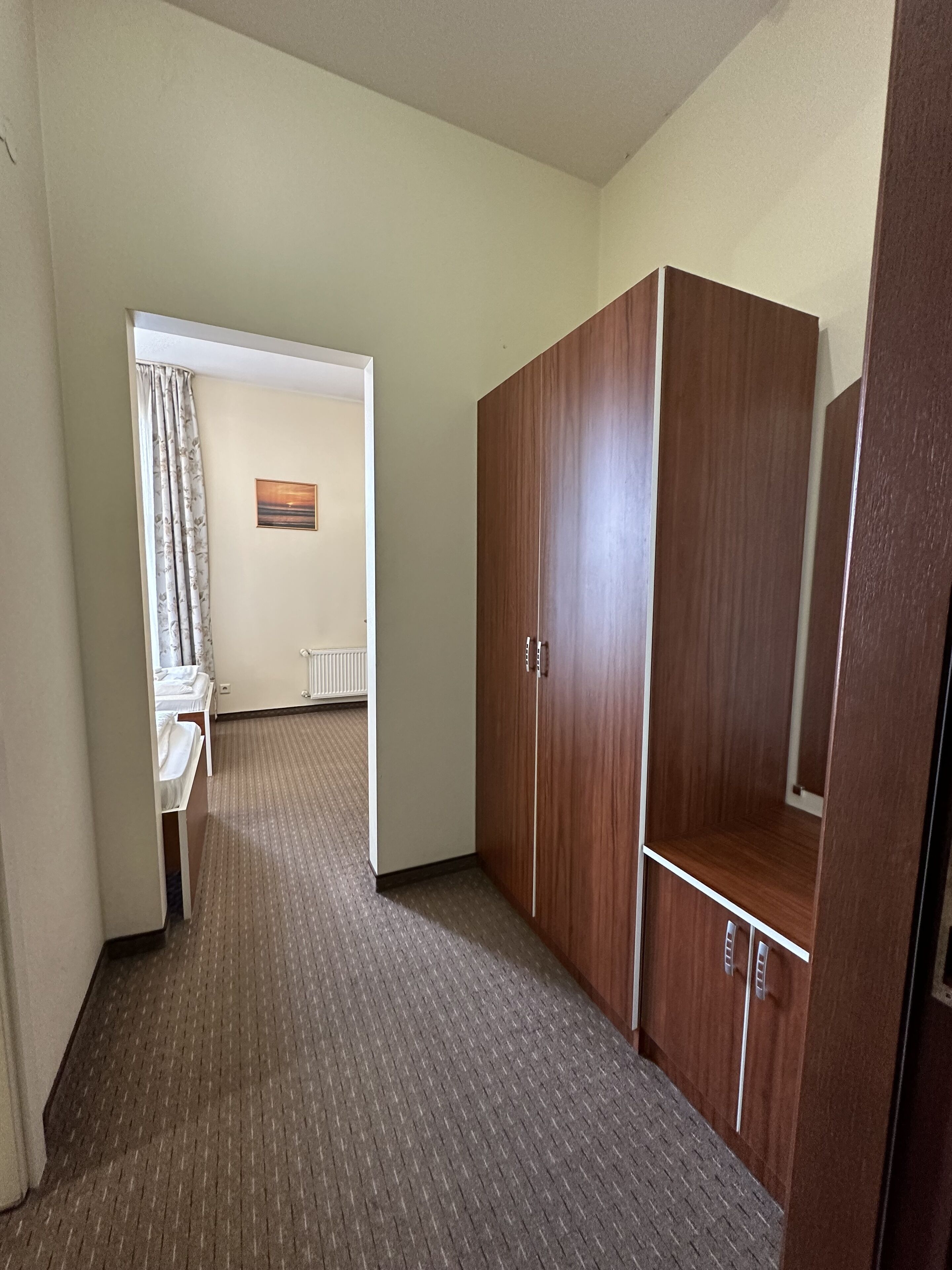 A hotel room with a bed, a wardrobe, and a radiator.