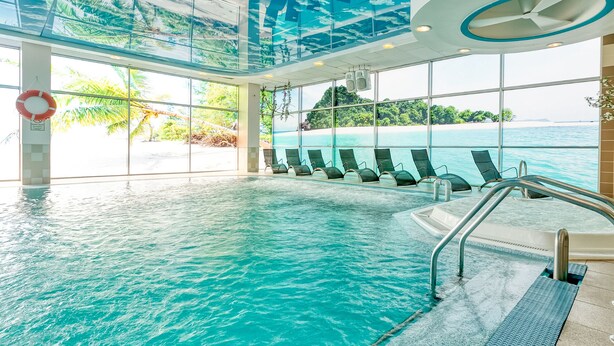 Una piscina interior con vistas despejadas al océano y un paisaje tropical.