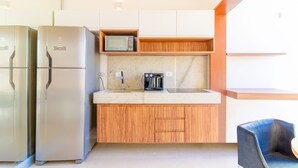 Eine moderne Küche mit Edelstahlgeräten, Holzschränken, einer Mikrowelle und einer Kaffeemaschine.