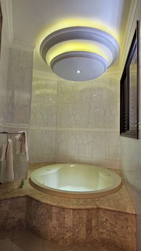 A bathroom with a marble vanity, a bathtub, and a towel rack.
