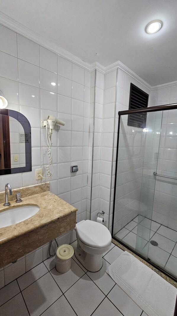 Un baño con lavamanos, espejo, inodoro y cabina de ducha acristalada.