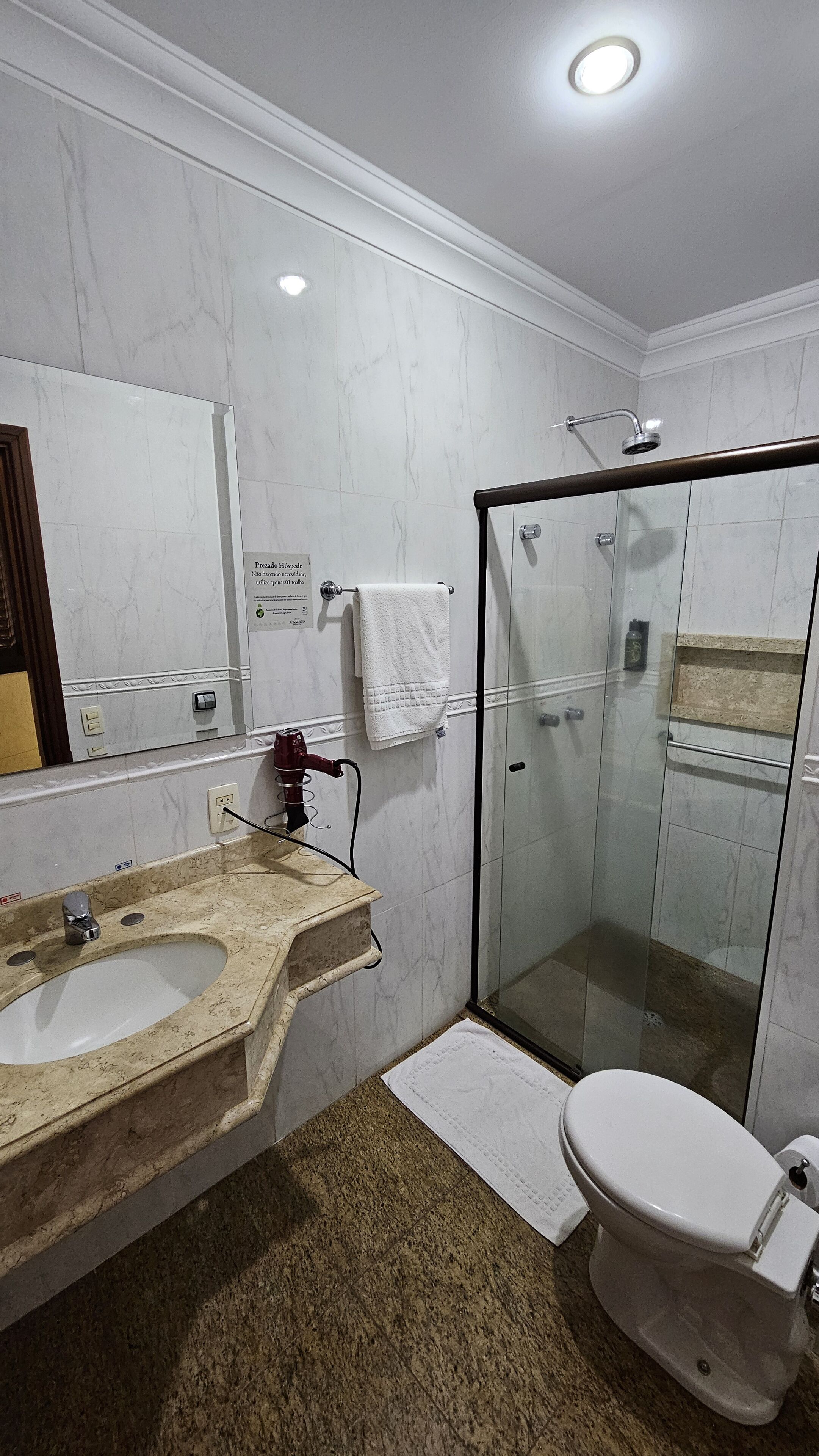 A modern bathroom with a glass-enclosed shower, a sink with a marble countertop, and a toilet.