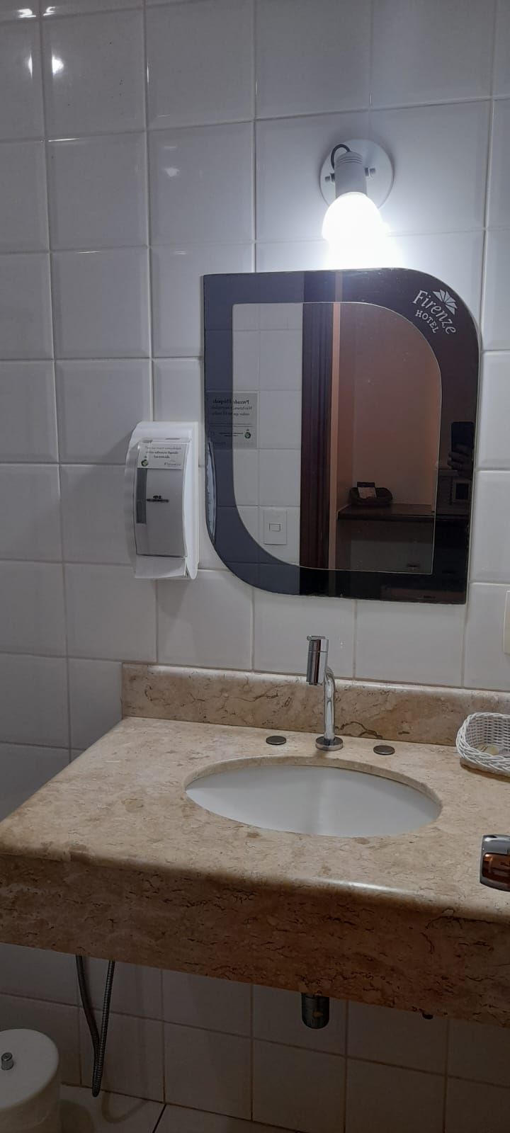 Ein Badezimmer mit Waschbecken, Spiegel und Handtuchspender.