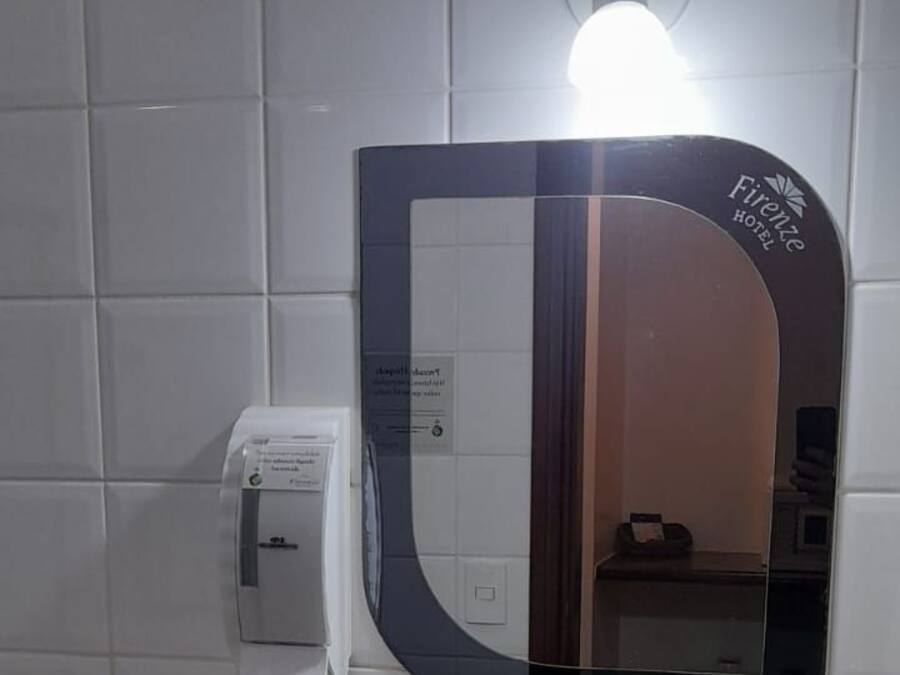 Ein Badezimmer mit Waschbecken, Spiegel und Handtuchspender.