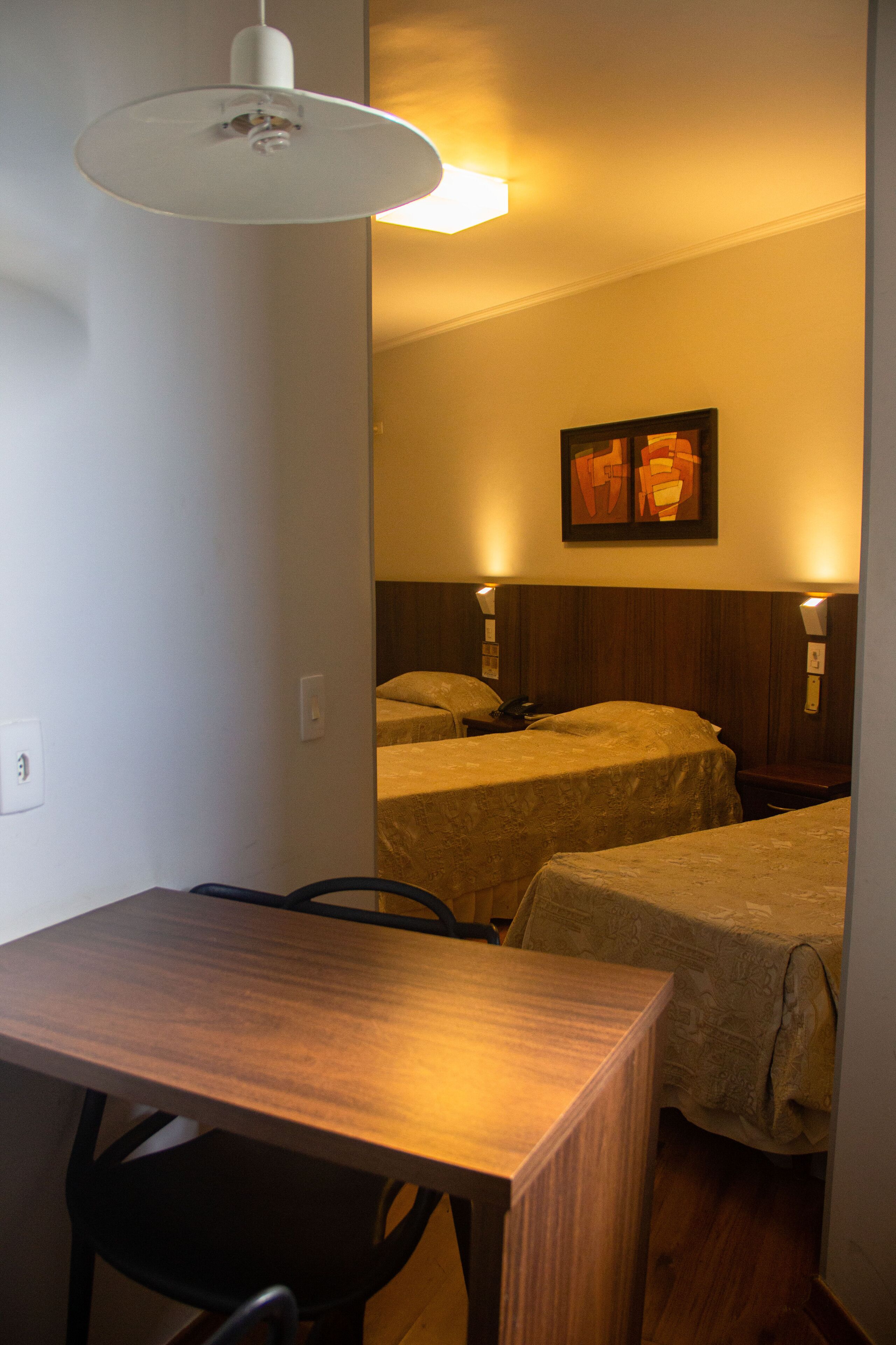 Une chambre d’hôtel avec deux lits, une table en bois et un bureau.