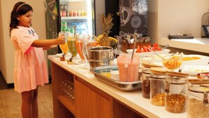 A buffet setup with various food and drink options, including a pineapple and a child serving drinks.