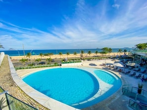 Una piscina al aire libre, sombrillas, sillones reclinables de piscina