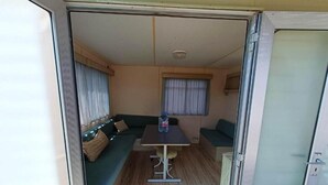 A compact RV interior with a dining area, a sofa, and a small table. - Sunset Milfontes (Odemira)