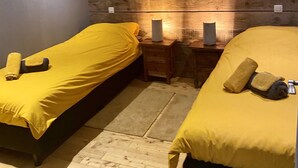 A hotel room with two beds, each with a yellow bedspread and a rolled towel. There is a wooden panel wall with a fox painting above the beds. - Gite Chalet in the Ardenne, Houffalize. Authentic but Renewed House for 9 People (Houffalize)