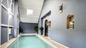 An indoor swimming pool with a tiled floor, surrounded by walls with a light blue color and a window. - Gite Chalet in the Ardenne, Houffalize. Authentic but Renewed House for 9 People (Houffalize)