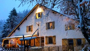 A two-story house with a snow-covered roof and a wooden fence. - Gite Chalet in the Ardenne, Houffalize. Authentic but Renewed House for 9 People (Houffalize)