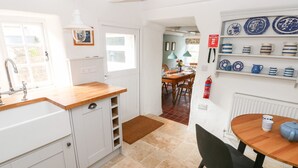 A kitchen with white cabinets, a wooden countertop, and a dining area with a table and chairs. - 10 Westgate Hill (Pembroke)