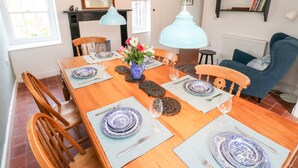 A dining area with a wooden table set for six, surrounded by chairs, with a bookshelf and a fireplace in the background. - 10 Westgate Hill (Pembroke)