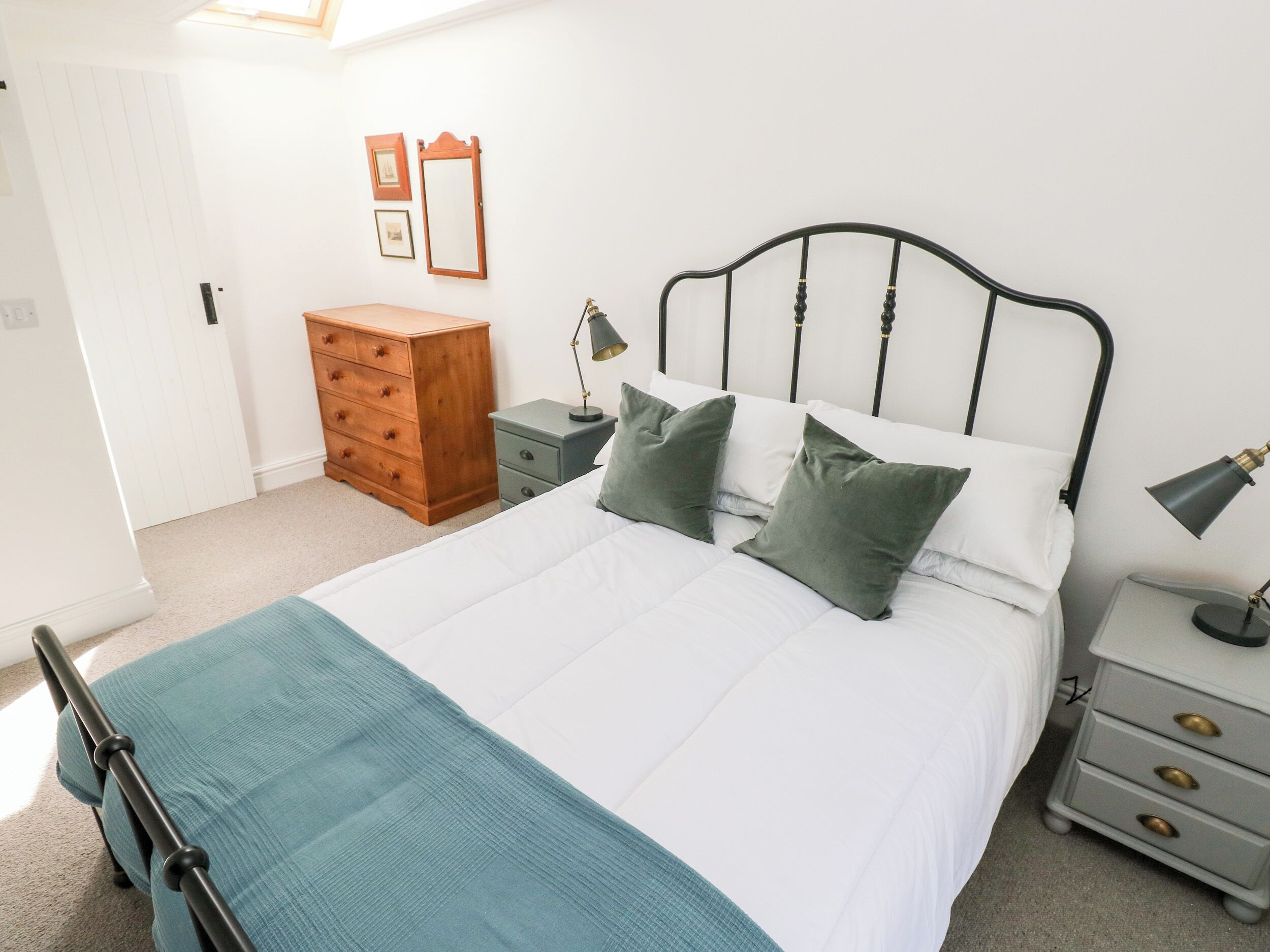 A neatly arranged bedroom with a bed, dresser, nightstands, and a mirror.