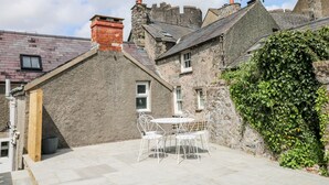 A stone building with a small patio area featuring a table and chairs. - 10 Westgate Hill (Pembroke)