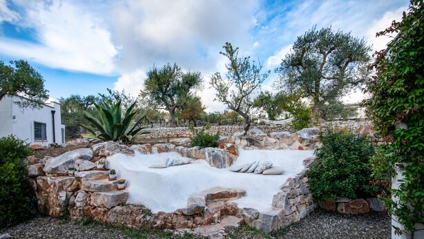 A stone pool surrounded by greenery and a white building. - Old trullo and lamia in one hectar garden pool with view. (Ostuni)