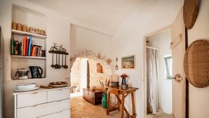 A rustic kitchen with a stone archway, wooden cabinets, and a dining table. - Old trullo and lamia in one hectar garden pool with view. (Ostuni)