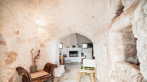 A stone-walled interior with a fireplace, a bench, and a chair. - Old trullo and lamia in one hectar garden pool with view. (Ostuni)