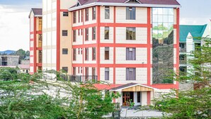 A multi-story hotel with a red and white facade, balconies, and a sign indicating it is the Ambrosia Hotel. - Ambrosia Hotel (Naivasha)