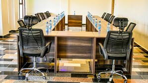 A conference room with a long table, black chairs, and water bottles. - Ambrosia Hotel (Naivasha)