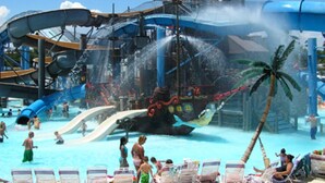 A water park with a pirate ship-themed water slide and a pool area with lounge chairs.