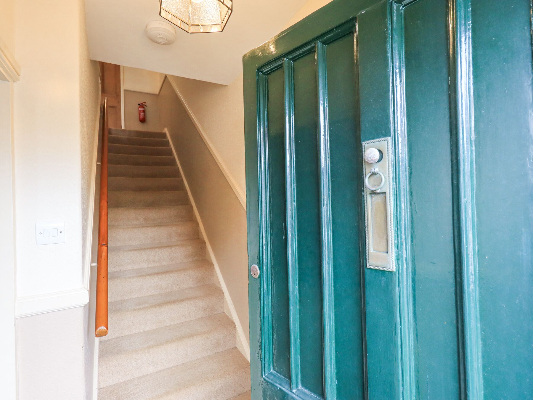 A staircase leading to a teal door with a keyhole and a small window.