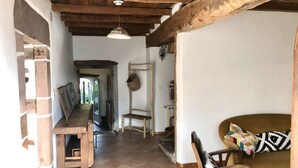 Un interno rustico caratterizzato da travi a vista in legno, un caminetto, un tavolo di legno e un divano con cuscini decorati.