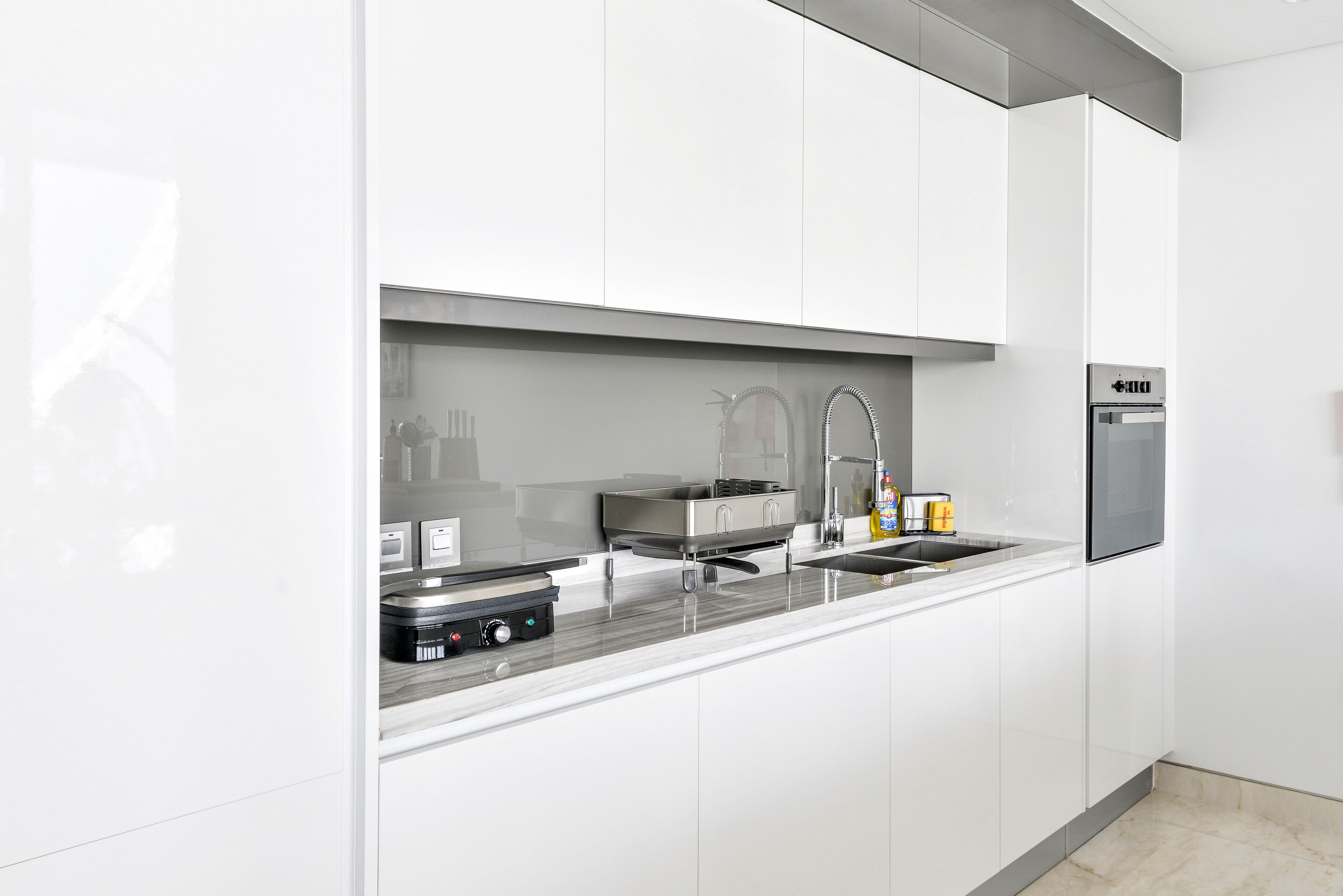 Une cuisine moderne avec des meubles blancs, des appareils en acier inoxydable et un plan de travail élégant.