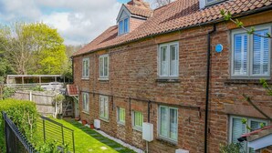 A two-story stone building with a tiled roof, multiple windows with shutters, and a well-maintained garden with a metal fence. - Amazing Guest Cottage in Nottingham with Parking! - Pass the Keys (Nottingham)