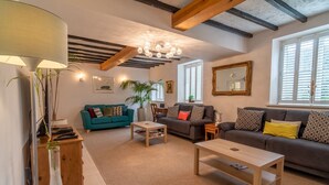 A cozy living room with a teal sofa, a wooden coffee table, and a large mirror on the wall. - Amazing Guest Cottage in Nottingham with Parking! - Pass the Keys (Nottingham)