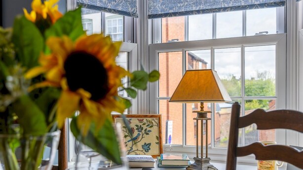 Une table à manger ornée d’un vase de tournesols, d’une lampe et d’un tableau encadré.