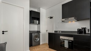 Cuina compacta amb rentadora, microones i forn.