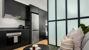 Una cuina moderna amb armaris foscos, un refrigerador d'acer inoxidable i un forn integrat.
