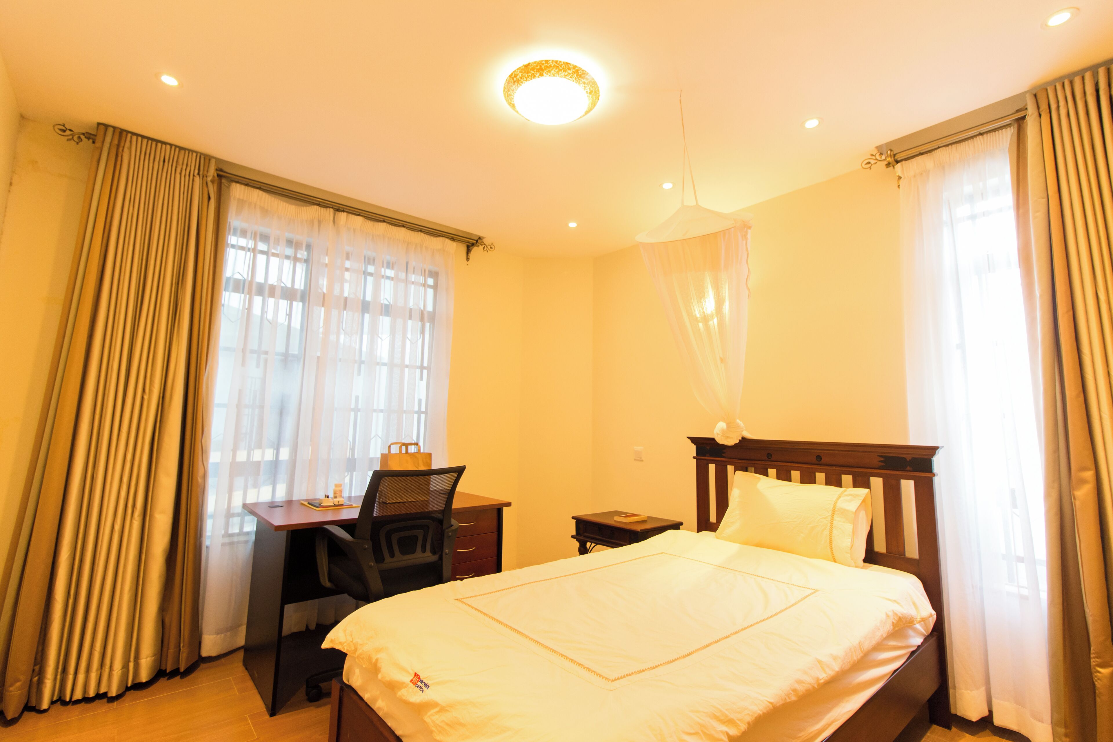 A hotel room with a bed, desk, chair, and a small table.