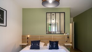 Une chambre à coucher avec un lit, des tables de chevet, un miroir et une fenêtre.