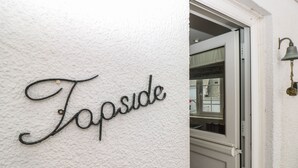 Paret blanca amb textura i la paraula "Fapside" escrita en lletres metàl·liques amb cal·ligrafia.