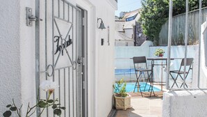 Edifici blanc amb una reixa de metall, una petita piscina i mobiliari exterior.