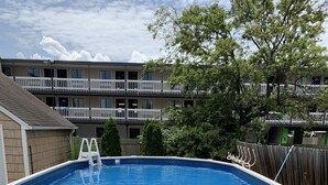 An above-ground swimming pool with a ladder, surrounded by a wooden fence and a grassy yard. - Bay View Bungalow by the Pier - Swimming Pool and Pet Friendly - 30 Day Listing (Norfolk)