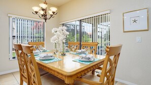 A dining room with a wooden table set for four, surrounded by chairs.