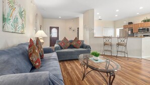 A living room with a sofa, a coffee table, and a kitchen in the background.